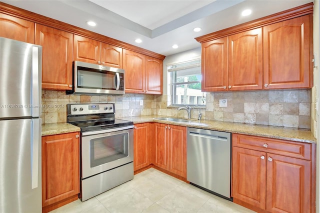 kitchen featuring light stone countertops, appliances with stainless steel finishes, backsplash, and sink