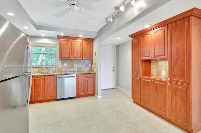 kitchen featuring backsplash, sink, ceiling fan, appliances with stainless steel finishes, and light stone counters