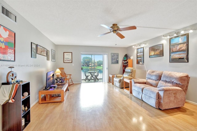 living room with ceiling fan, a textured ceiling, and light hardwood / wood-style flooring