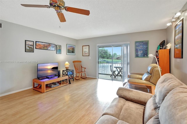 living room with ceiling fan, a textured ceiling, and light hardwood / wood-style flooring