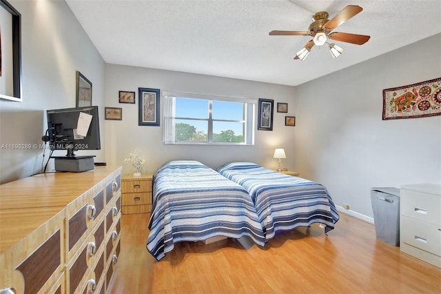 bedroom with a textured ceiling, hardwood / wood-style flooring, and ceiling fan