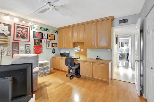 office space with a textured ceiling, built in desk, light hardwood / wood-style floors, and ceiling fan