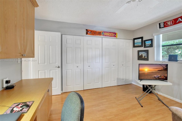 home office with ceiling fan, light wood-type flooring, and a textured ceiling