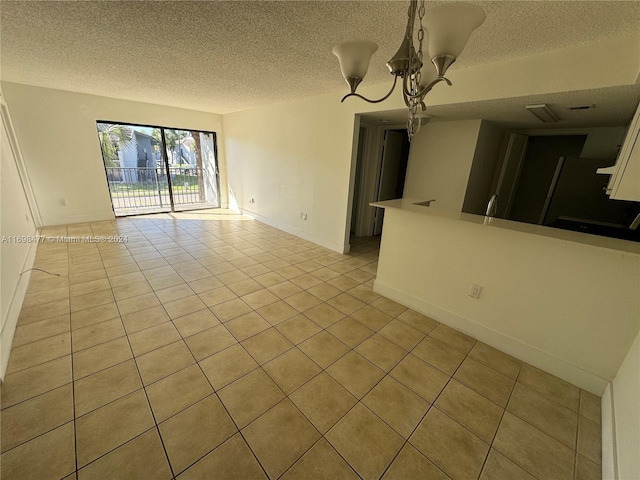 empty room with light tile patterned floors, a textured ceiling, and a notable chandelier