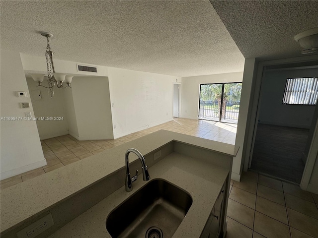 kitchen featuring sink, pendant lighting, a textured ceiling, and an inviting chandelier