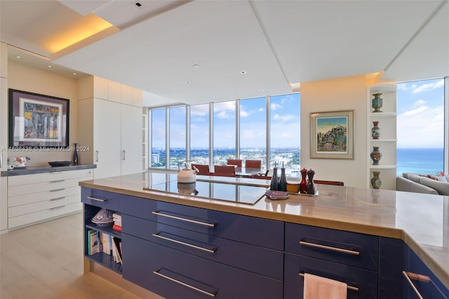 kitchen featuring blue cabinetry, floor to ceiling windows, stovetop, a water view, and light wood-type flooring