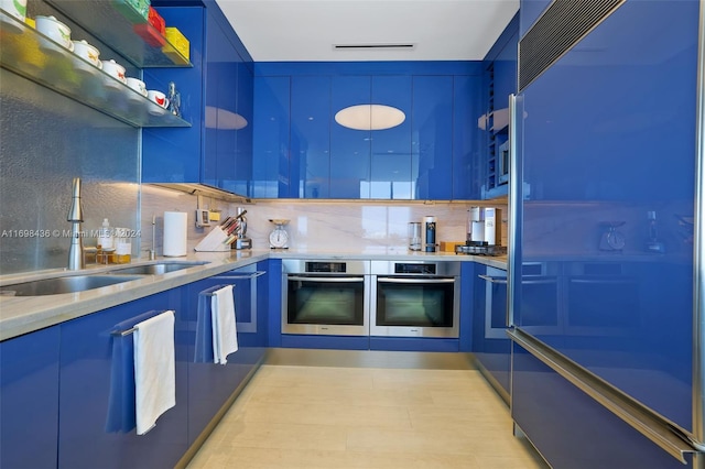 kitchen with oven, decorative backsplash, blue cabinets, and sink