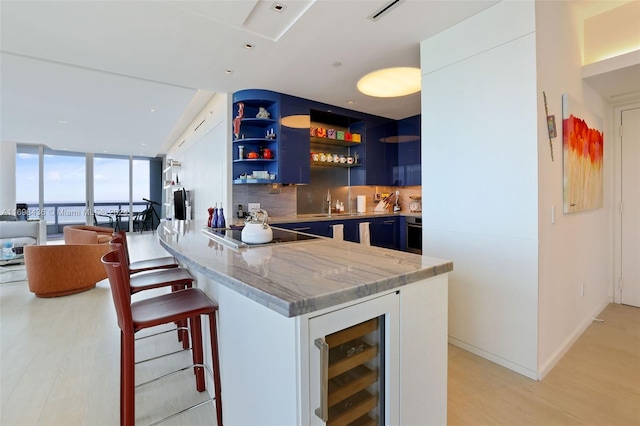 bar featuring black electric stovetop, wine cooler, light hardwood / wood-style flooring, tasteful backsplash, and white cabinetry