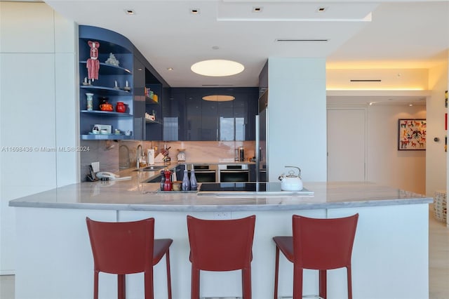 kitchen featuring kitchen peninsula, decorative backsplash, white cabinetry, and a kitchen breakfast bar