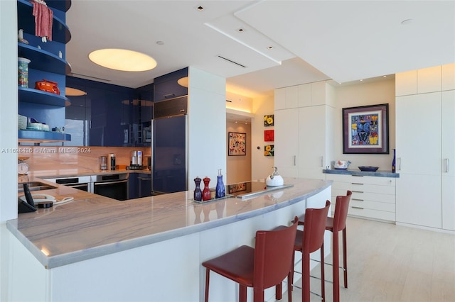 kitchen with white cabinetry, stainless steel oven, tasteful backsplash, built in fridge, and kitchen peninsula