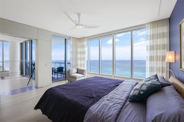 bedroom featuring light wood-type flooring, a water view, and multiple windows