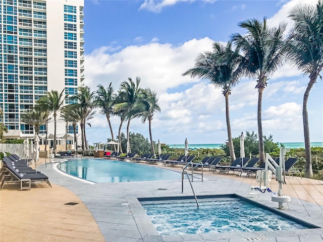 view of swimming pool with a patio area, a jacuzzi, and a water view