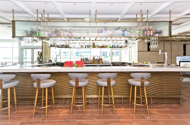 bar with wood-type flooring and coffered ceiling