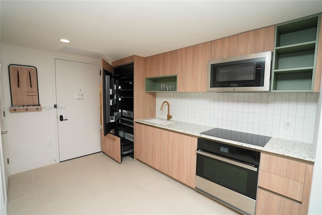 kitchen featuring backsplash, sink, light stone countertops, light brown cabinetry, and stainless steel appliances