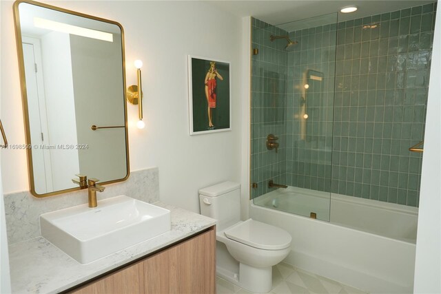 full bathroom featuring tiled shower / bath combo, toilet, and vanity