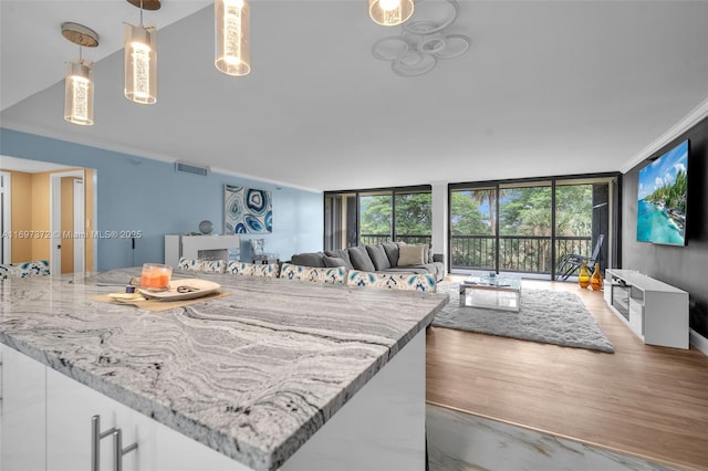 kitchen featuring light stone counters, hanging light fixtures, floor to ceiling windows, and white cabinets