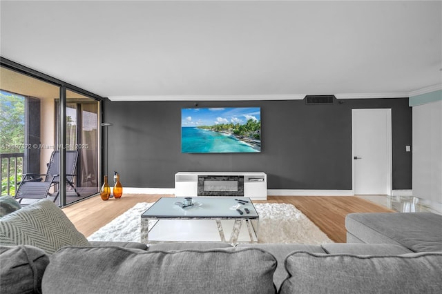 living room with crown molding, hardwood / wood-style floors, and a wall of windows