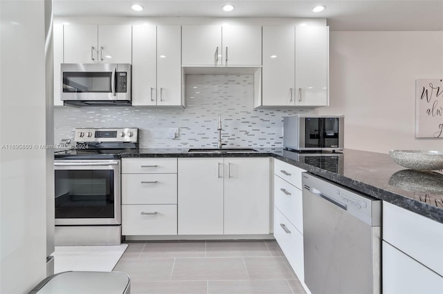 kitchen with dark stone countertops, sink, white cabinetry, and stainless steel appliances