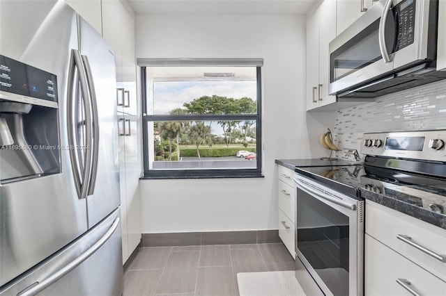 kitchen with decorative backsplash, white cabinets, dark stone counters, and appliances with stainless steel finishes