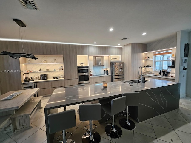 kitchen with sink, a spacious island, light tile patterned floors, and stainless steel appliances