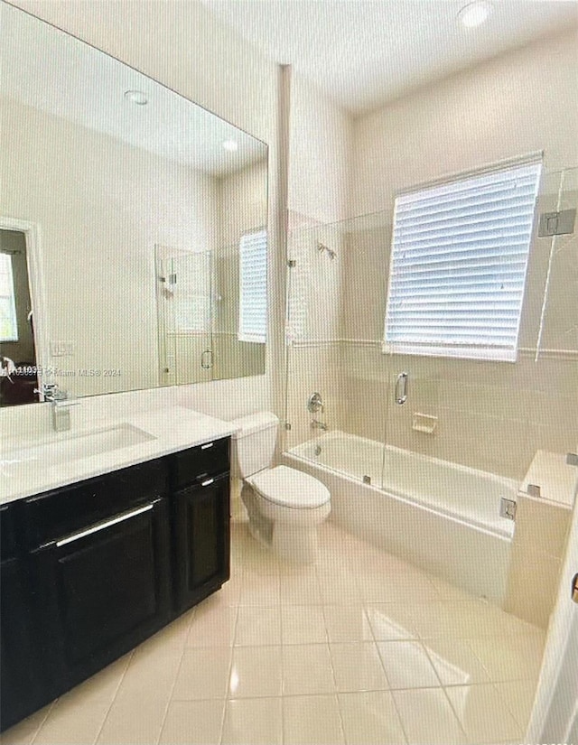 full bathroom with tile patterned floors, vanity, toilet, and bath / shower combo with glass door