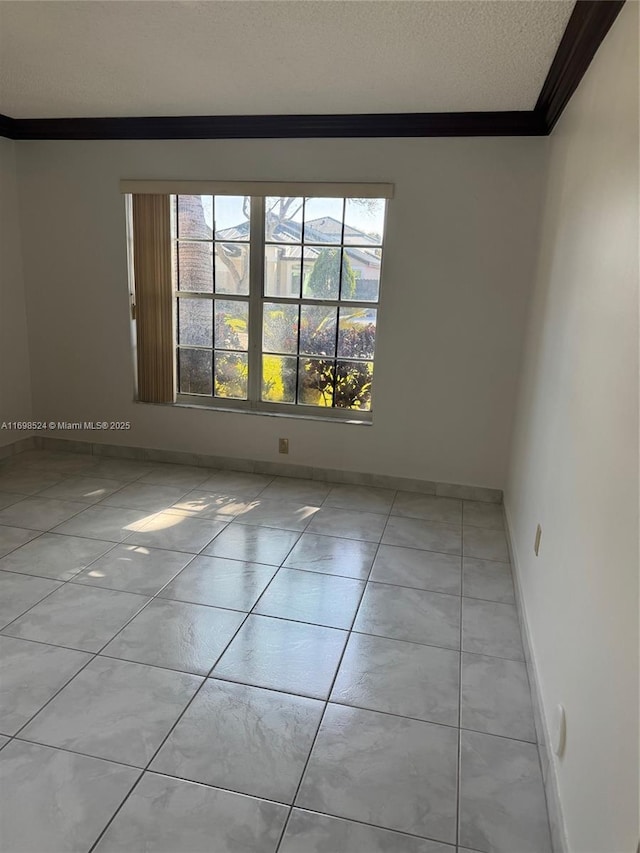 tiled spare room featuring a textured ceiling and ornamental molding