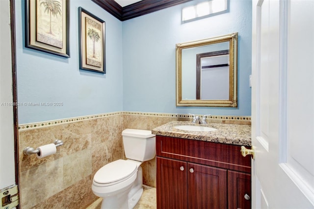 bathroom with vanity, toilet, ornamental molding, and tile walls