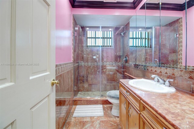 bathroom featuring a shower with shower door, toilet, vanity, and ornamental molding