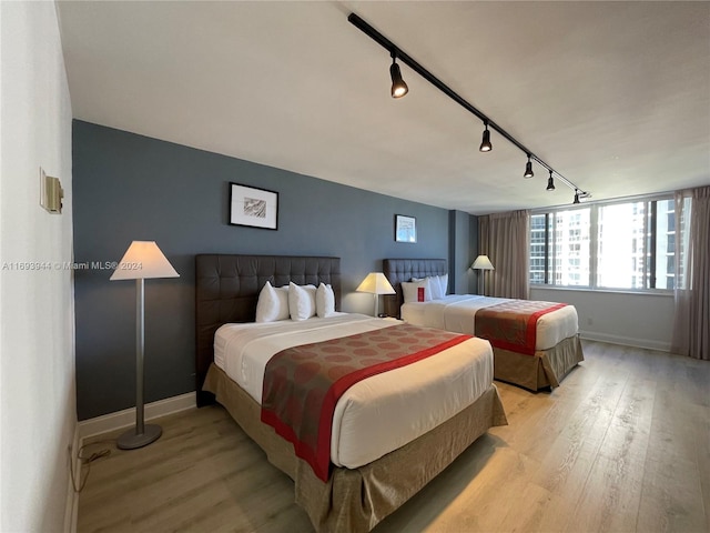 bedroom with rail lighting and light hardwood / wood-style flooring