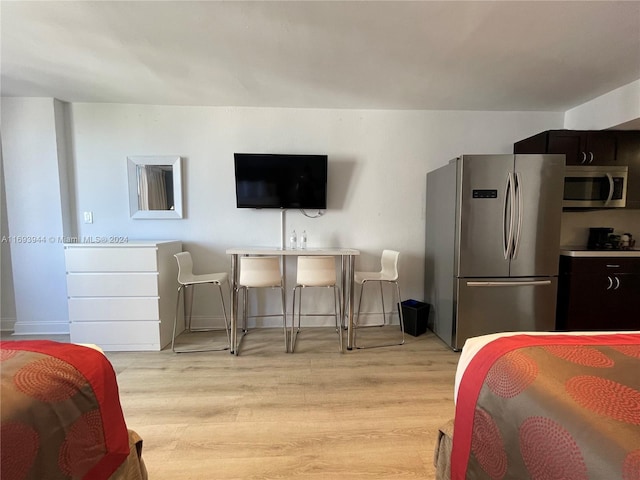 bedroom featuring stainless steel refrigerator and light hardwood / wood-style flooring