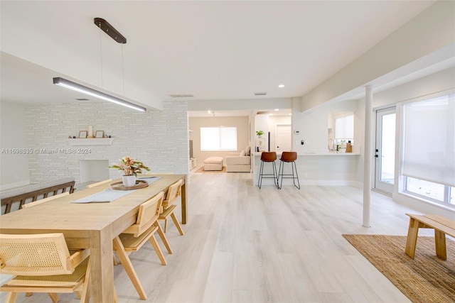 dining space featuring light wood-type flooring and brick wall