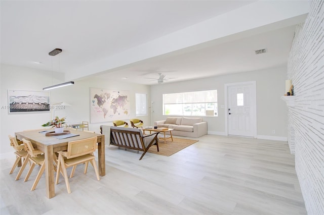 dining room featuring ceiling fan, a large fireplace, and light wood-type flooring