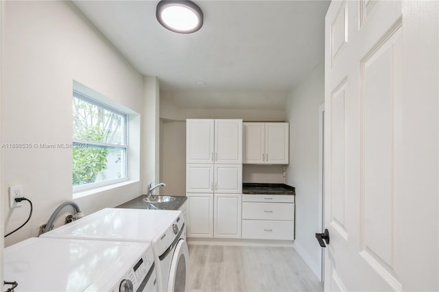 laundry area with washing machine and dryer, light hardwood / wood-style flooring, and cabinets