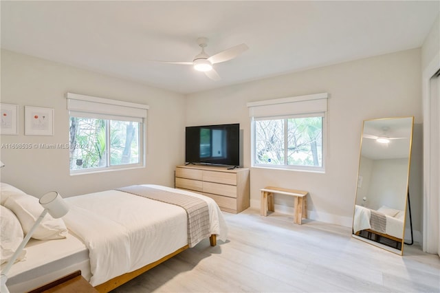 bedroom featuring ceiling fan, light hardwood / wood-style floors, and multiple windows