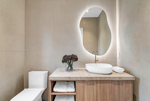 bathroom featuring vanity, toilet, and tile walls