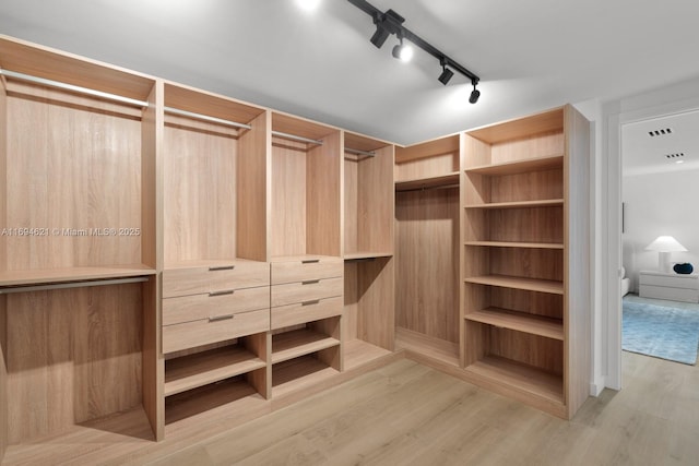 walk in closet with light hardwood / wood-style floors