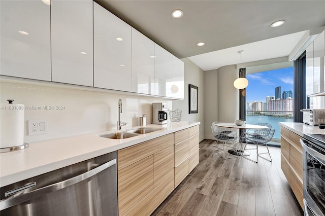 kitchen featuring pendant lighting, white cabinets, sink, light hardwood / wood-style flooring, and appliances with stainless steel finishes