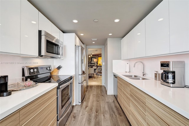 kitchen with white cabinets, stainless steel appliances, light hardwood / wood-style flooring, and sink