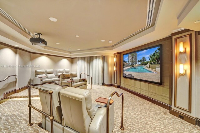 carpeted cinema room featuring a raised ceiling and crown molding