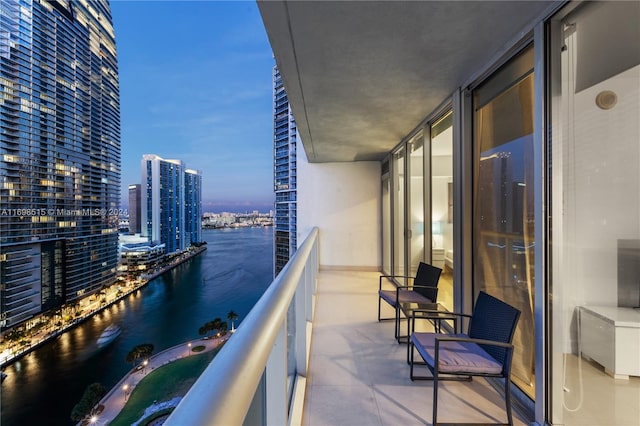 balcony at dusk featuring a water view