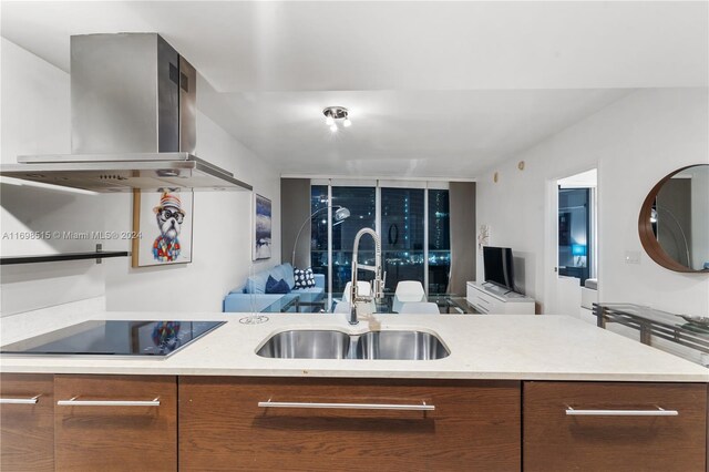 kitchen featuring wall chimney range hood, sink, and black electric cooktop