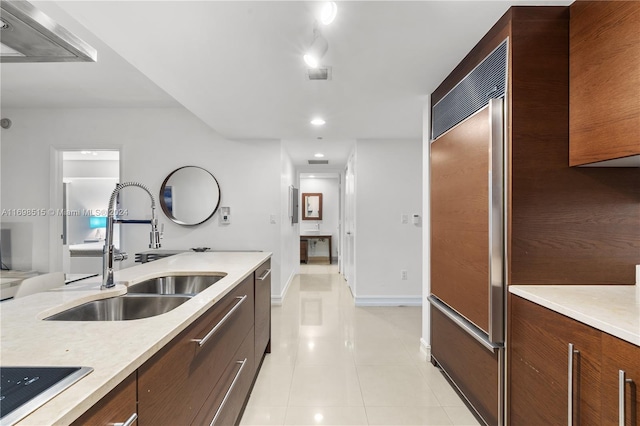 kitchen featuring built in fridge, sink, light tile patterned floors, and black cooktop