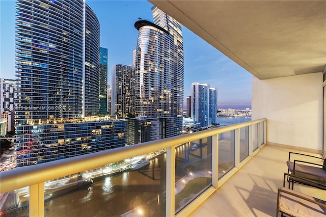 balcony at dusk featuring a water view