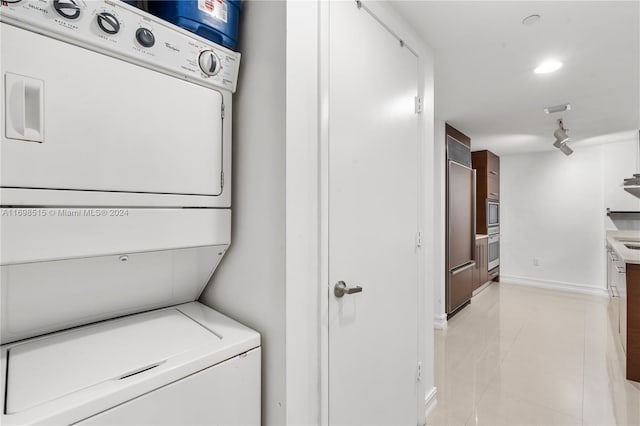 clothes washing area with light tile patterned floors and stacked washer and dryer