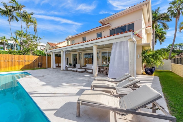 back of house featuring a fenced in pool, outdoor lounge area, a patio area, and ceiling fan