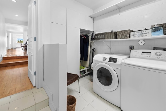 clothes washing area with washing machine and dryer and light hardwood / wood-style floors