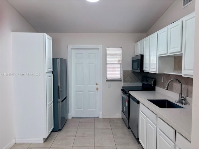 kitchen featuring appliances with stainless steel finishes, white cabinetry, sink, backsplash, and light tile patterned floors