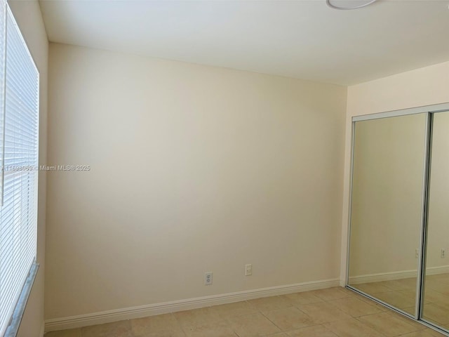 unfurnished bedroom featuring light tile patterned flooring and a closet