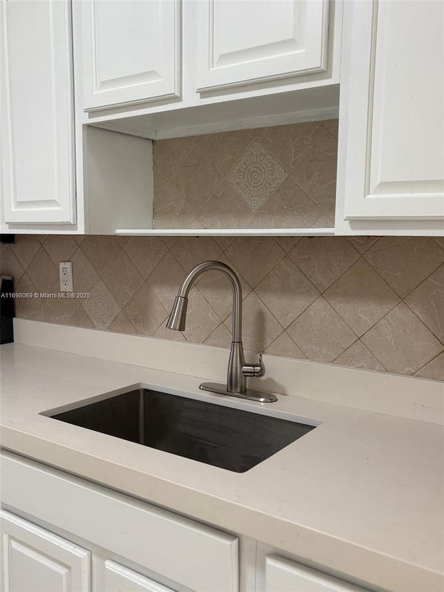 kitchen featuring tasteful backsplash, sink, and white cabinets