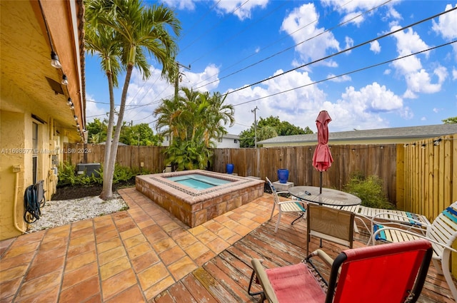 view of patio with central AC unit and an in ground hot tub